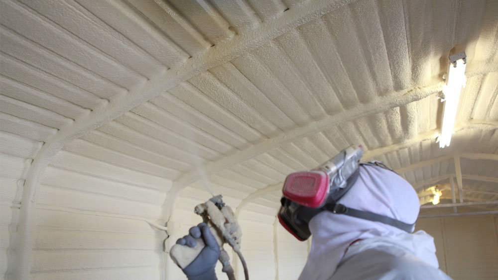 Closed-cell spray foam insulation being applied to the interior steel panels of a metal building in Kansas City